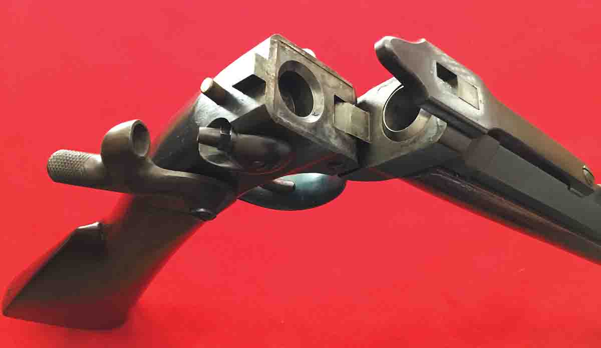 The Smith receiver is shown in the open position. Note the top of the brass lifter rod, locking lug, split chamber and large locking spring. The lifter rod raises the rear end of the large spring to clear the lug, thereby allowing the barrel to rotate downward, which opens the chamber for loading. On closing, the rectangular hole in the large spring snaps down over the rectangular lug, locking the breech.